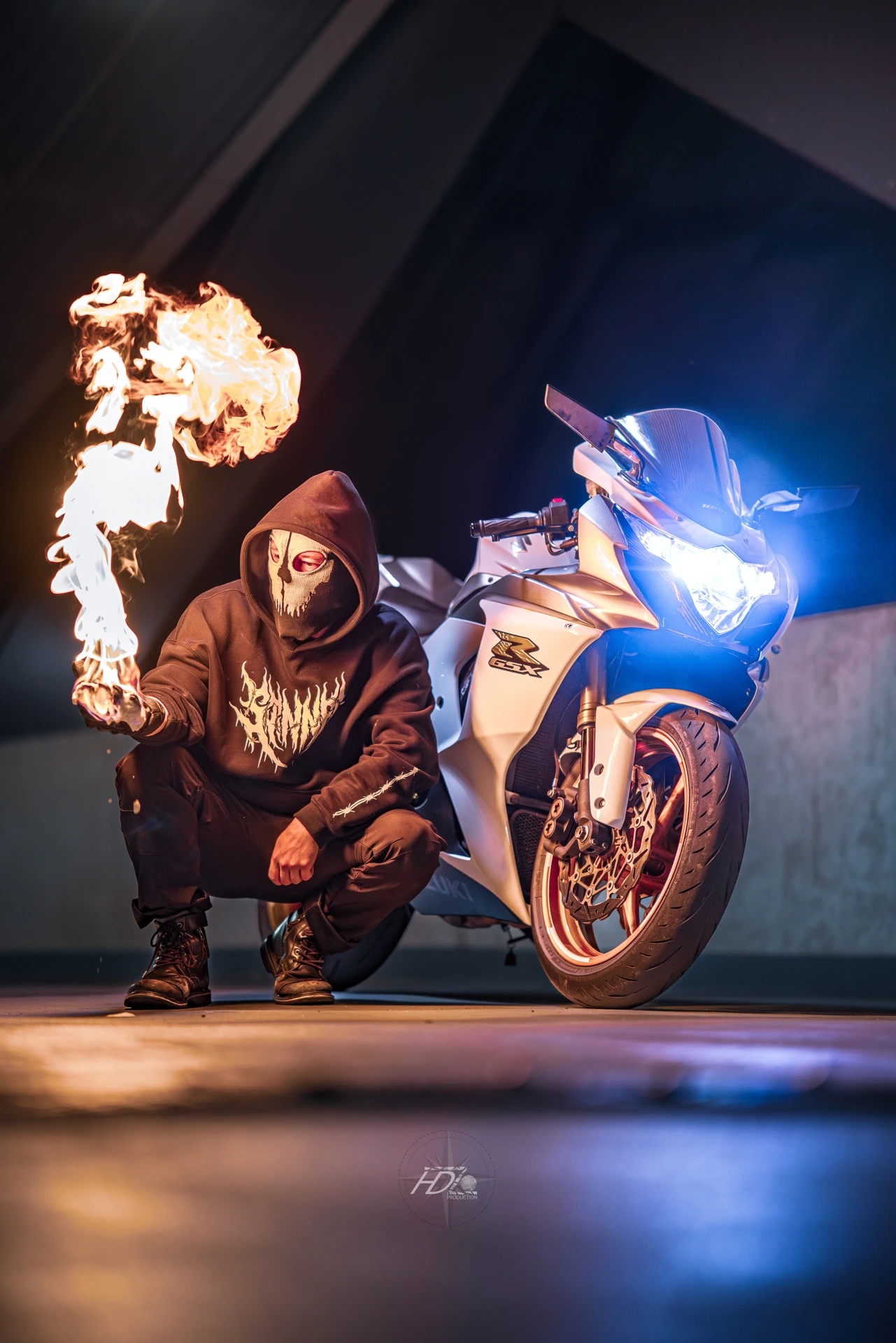 Un motard pose à côté de sa moto avec une flamme dans la main.