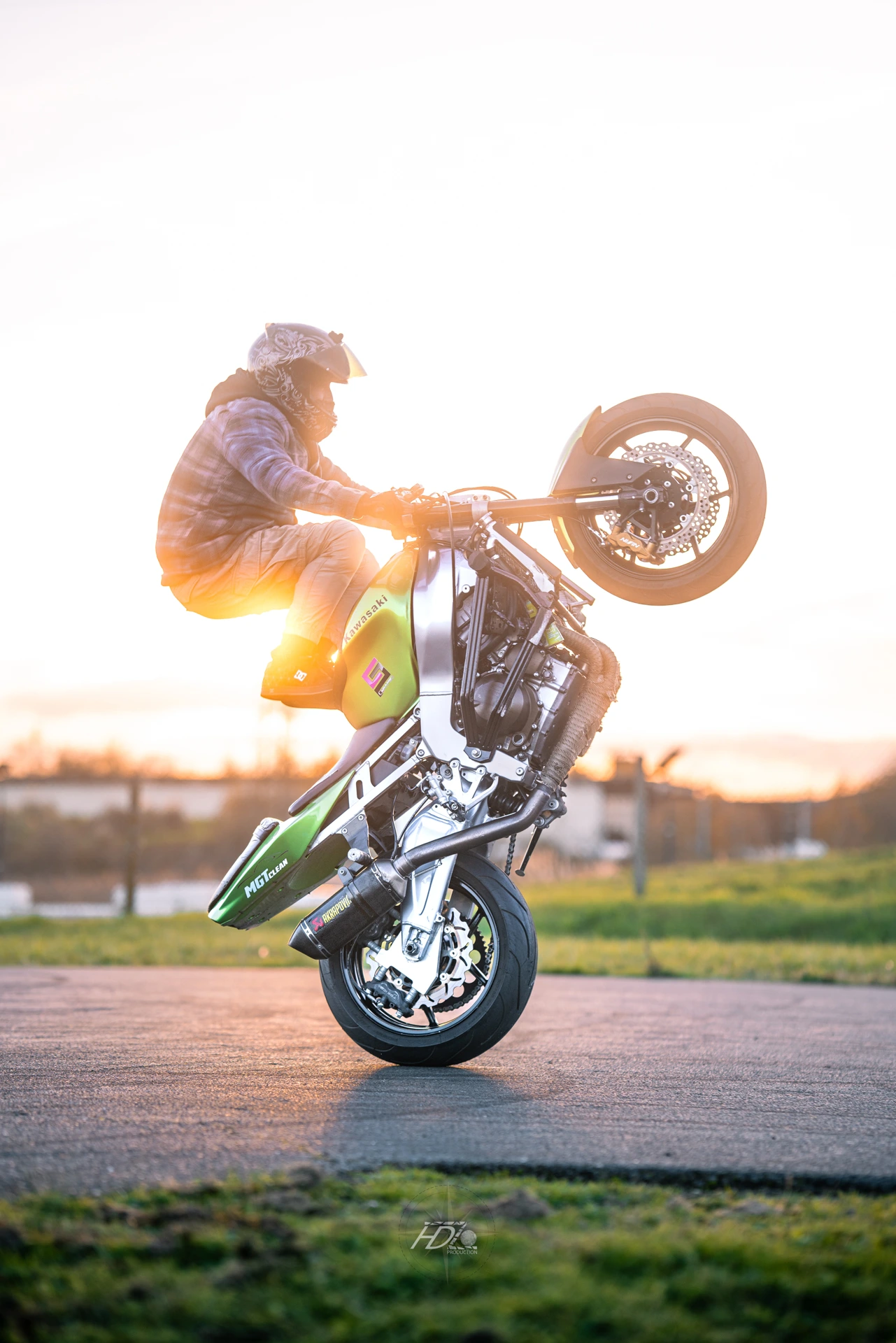 Un motard fait une figure de stunt avec les pieds sur le réservoir.