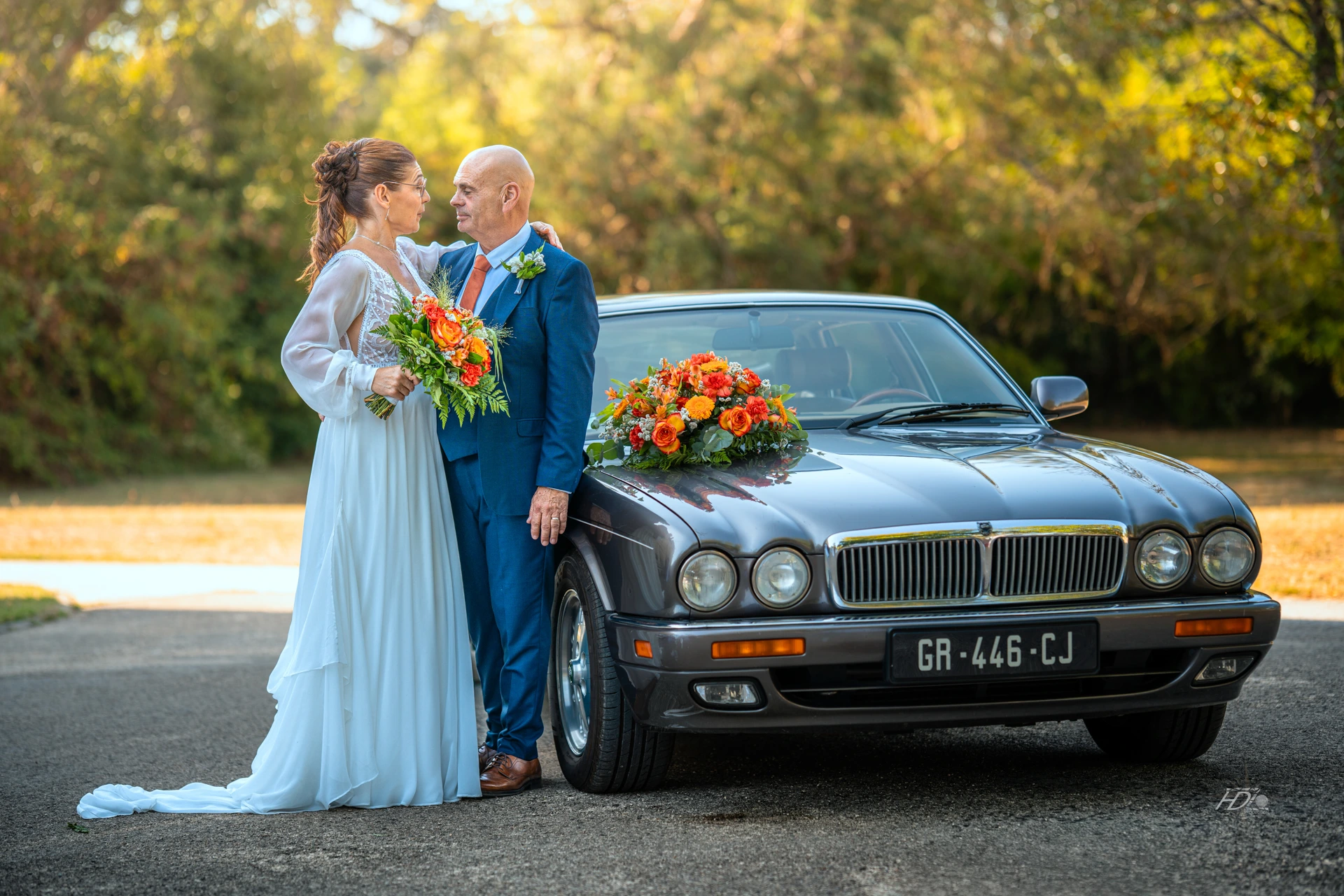 Les mariées qui posent devant leur voiture lors de leur séance avec leur photographe de mariage à Saint-Émilion à côté de Bordeaux.
