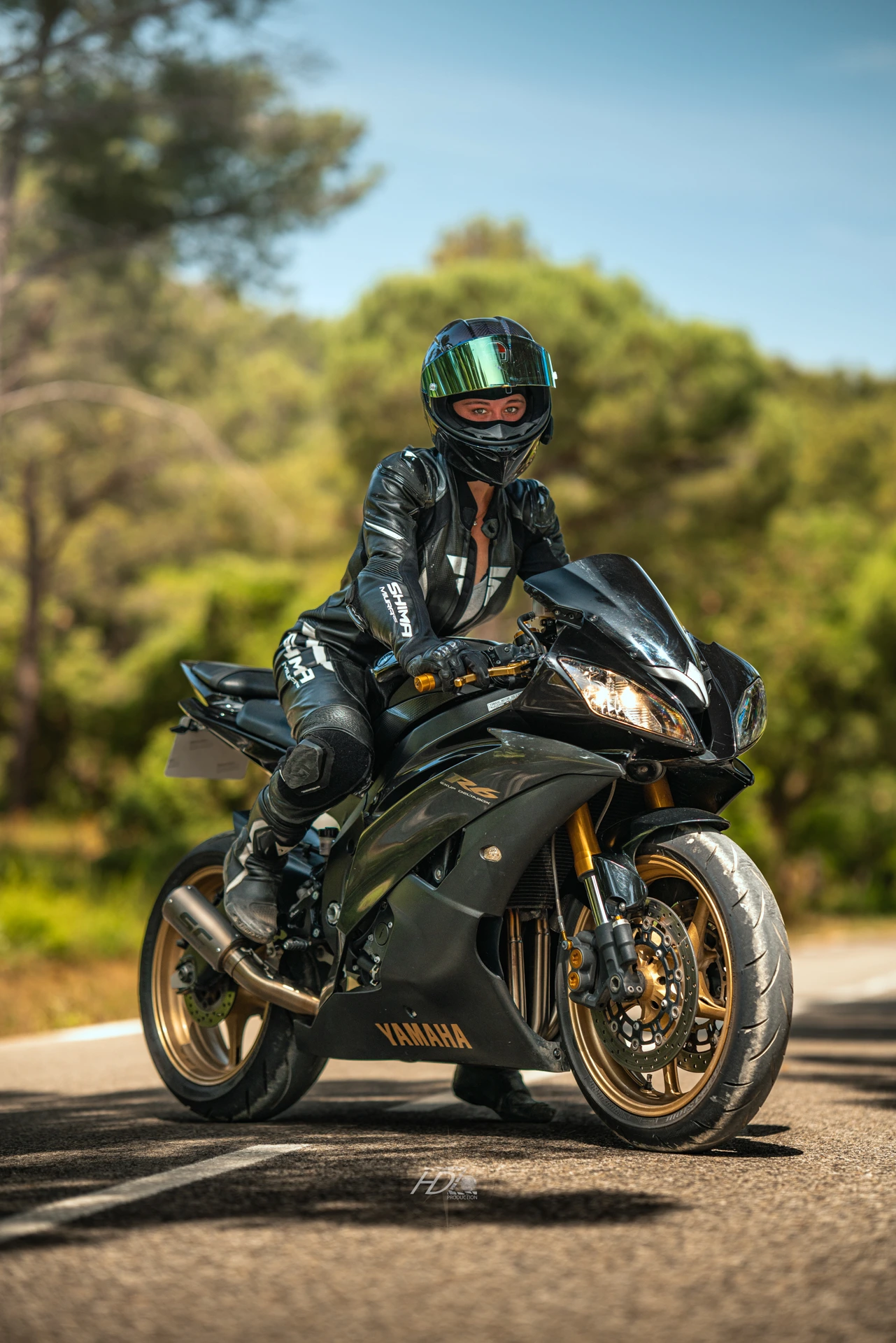 Une femme motarde pose avec une combinaison de moto tout en cuir.