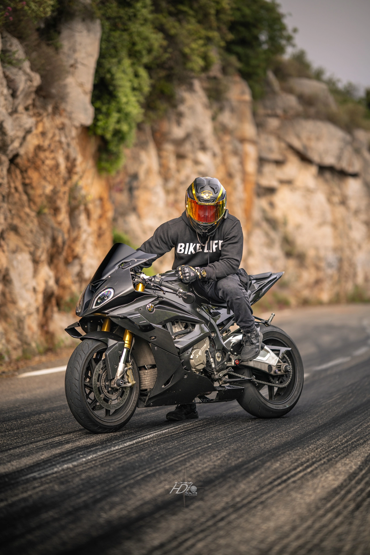 Un motard est assis sur sa moto devant des traces de pneus sur la route.