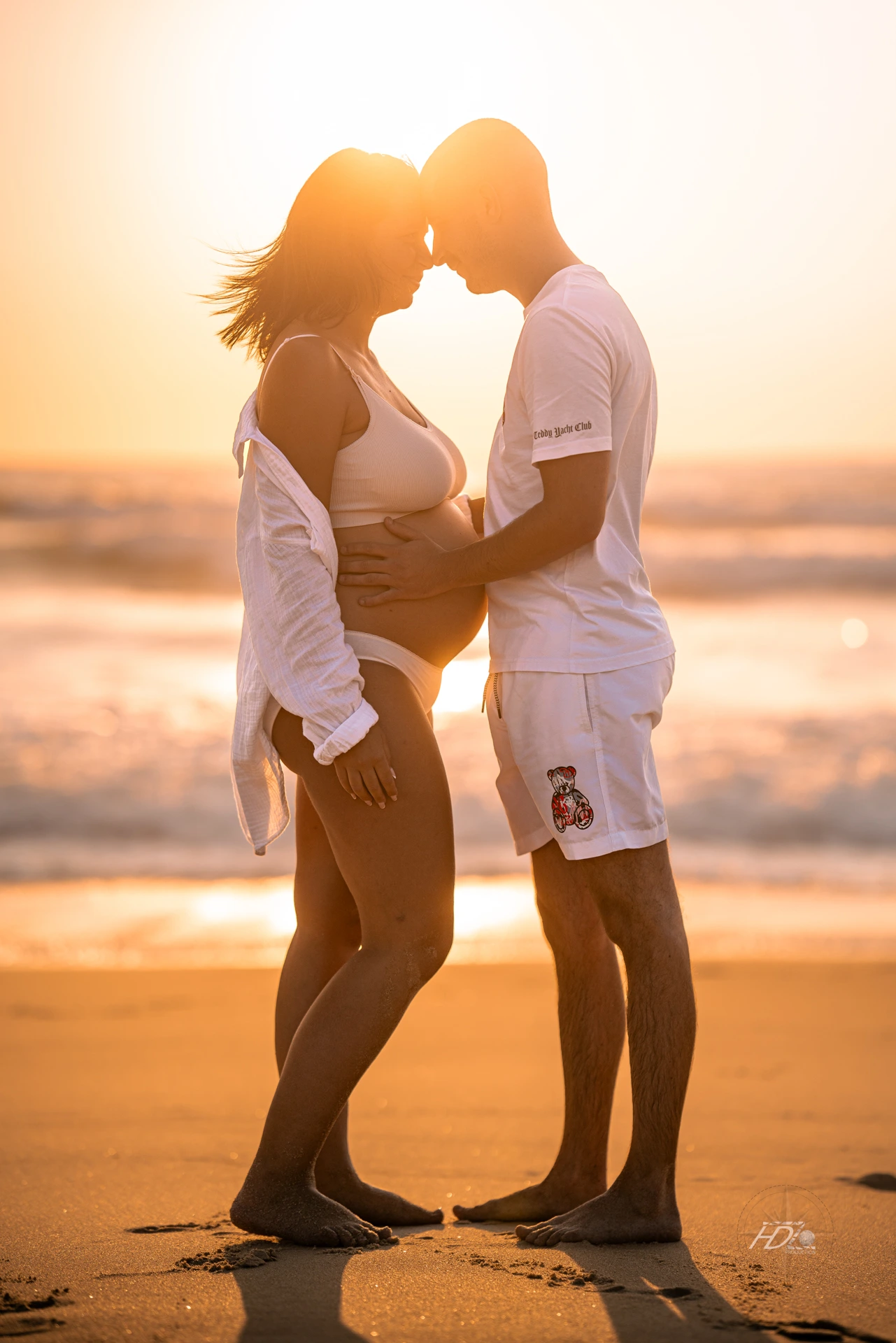 Un couple proche lors d'un shooting grossesse à Arcachon avec le coucher du soleil