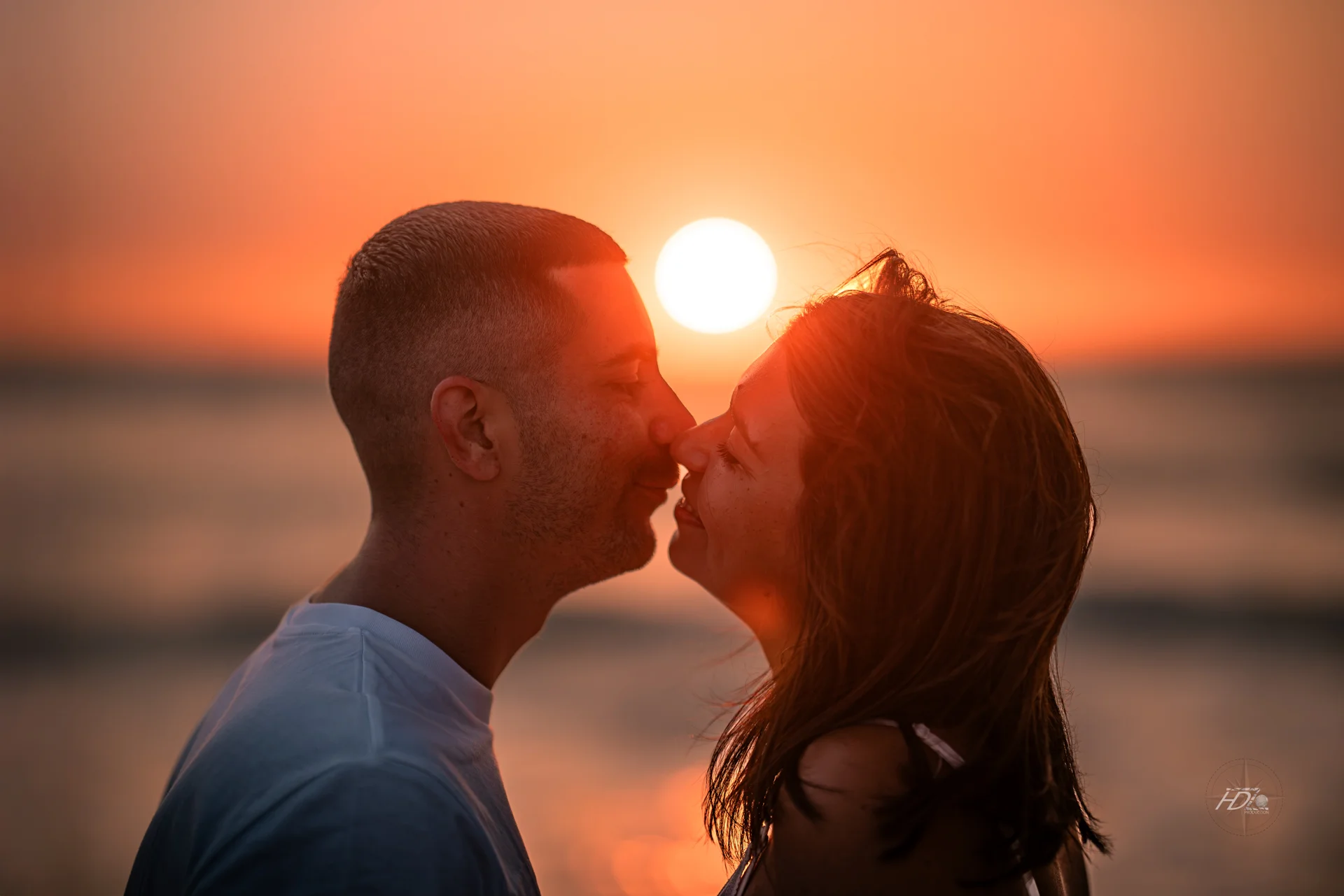 Un couple s'embrassant lors d'un coucher soleil pendant une séance photo grossesse à la plage à côté de Bordeaux