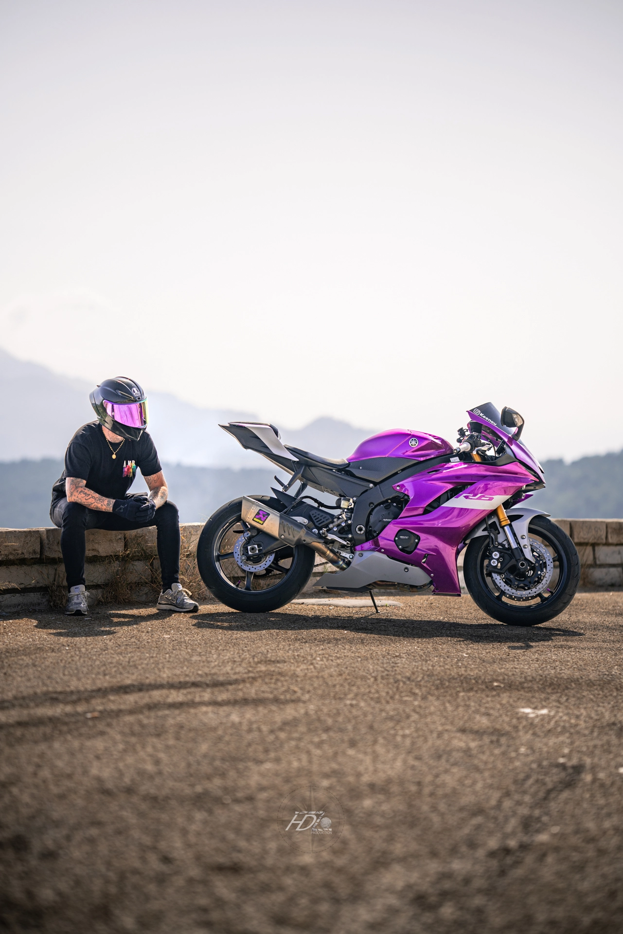 Un motard est assis sur le bord de la route avec sa moto à côté.