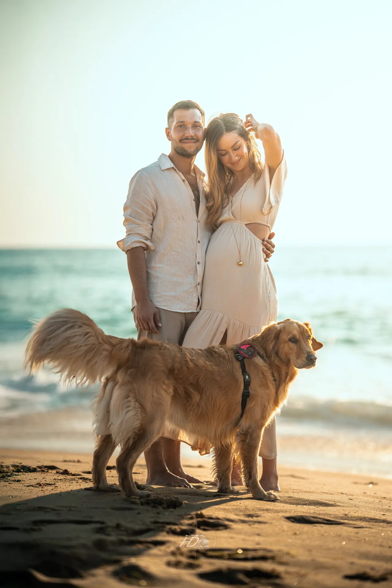Un couple avec leur chien lors d'une séance photo grossesse à la plage à côté de Bordeaux