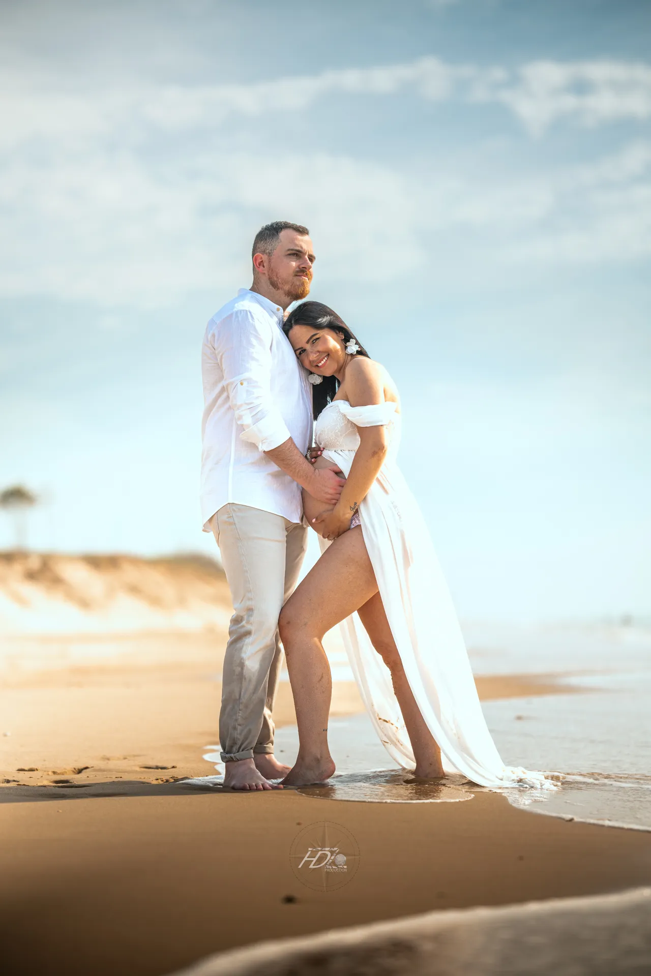 Un couple se tenant dans les bras lors d'une séance photo grossesse à la plage à côté de Bordeaux