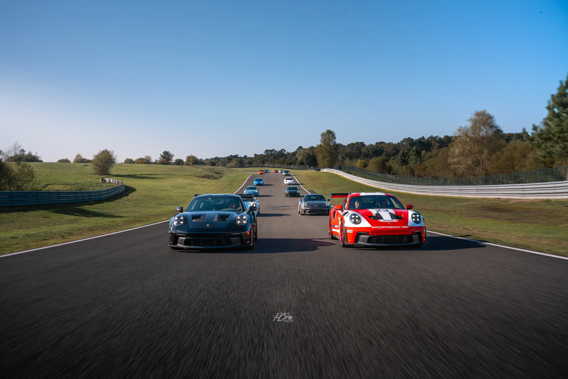 Des voitures Porsche alignés les unes à côté des autres en roulant sur un circuit.