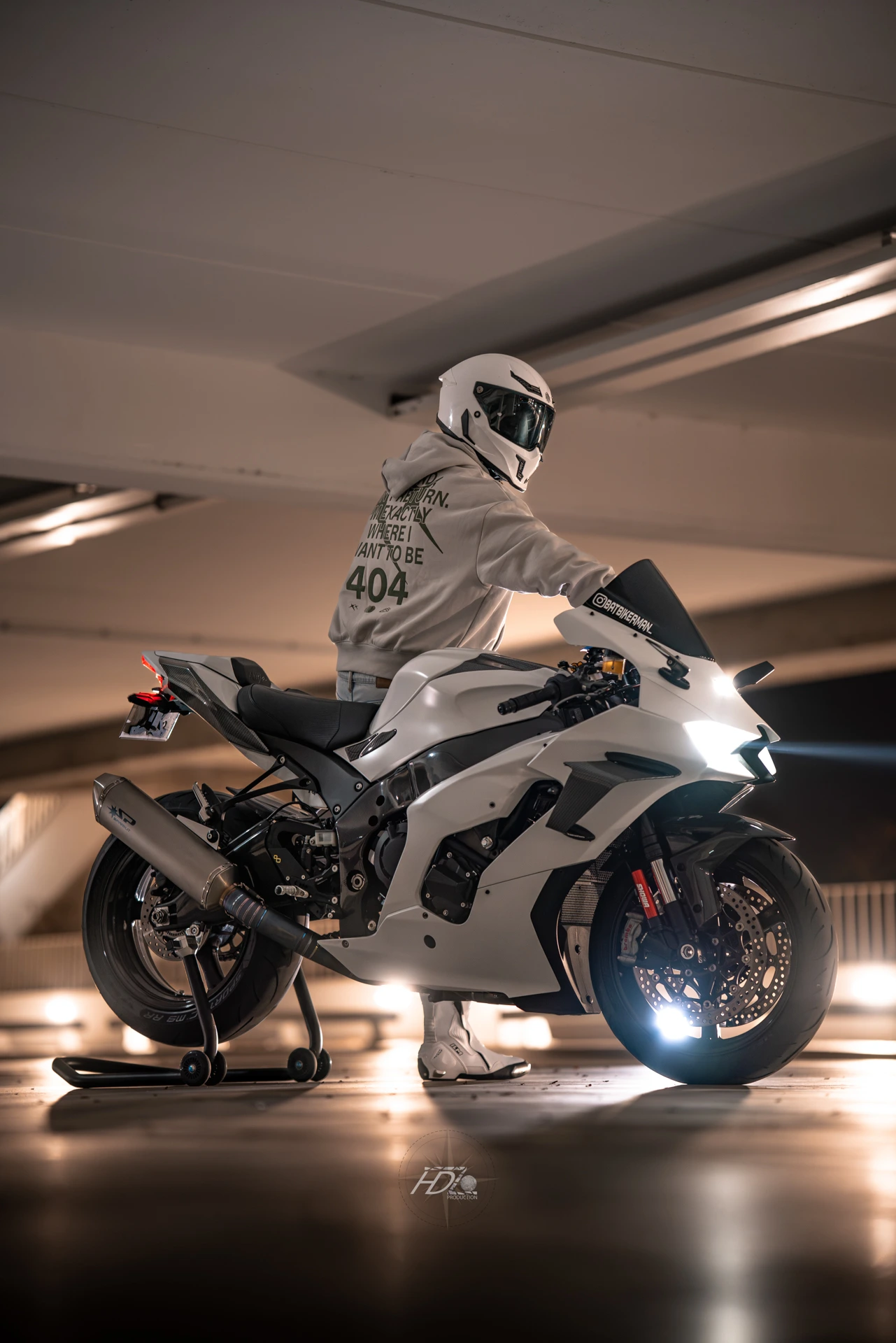 Un motard et sa moto dans un parking la nuit.