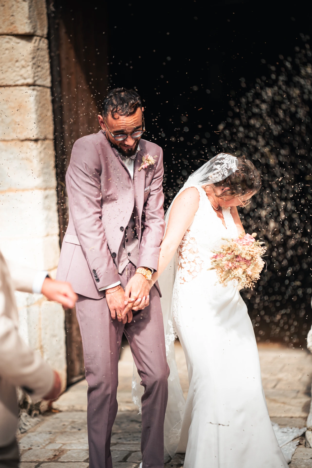 Les mariées sortant de la cérémonie religieuse recevant les fleurs séchées lors de leur mariage à Angoulême immortalisé par leur photographe mariage.